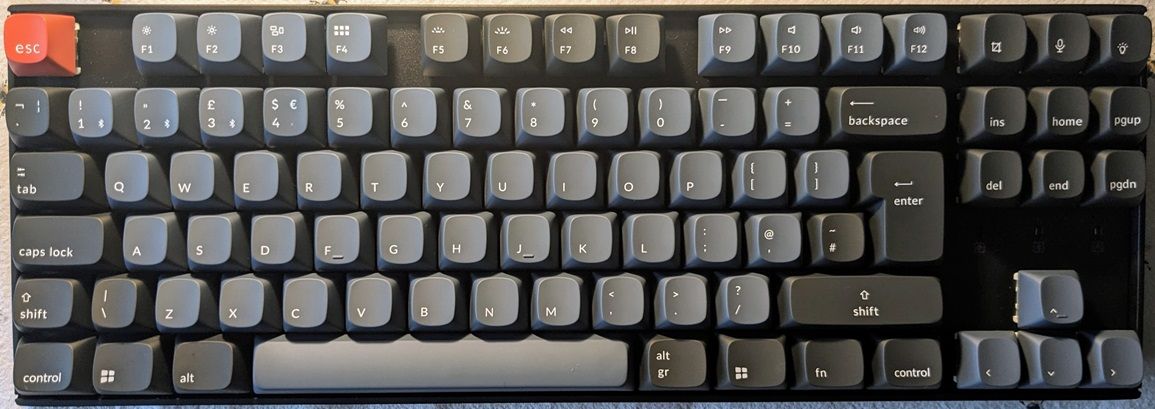 Photograph of the assembled Keychron K8 pro with the UK Windows key setup.  The colours are predominantly a dark blue/grey.