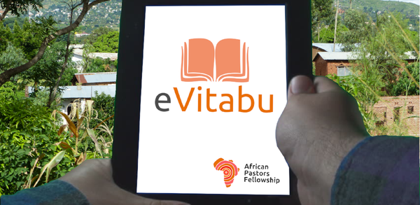 Photograph of a man holding a tablet with eVitabu and APF logos on it.  Africa is shown in the background,